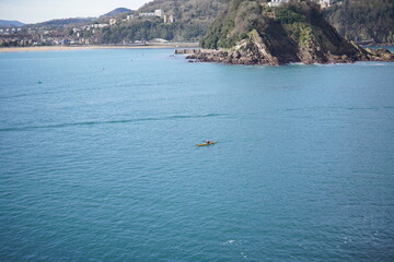 Fototapeta premium Lone kayaker paddling on calm turquoise sea near San Sebastian, Spain