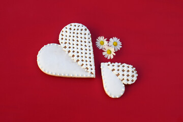 Gingerbread hearts decorated with white icing, with daisy flowers, red background
