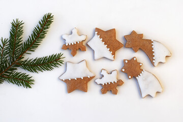 Decorated gingerbread cookies on a white background with spruce twig. Christmas baking