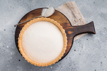 Versatile white sugar in a rustic bowl, ready to enhance desserts and beverages with its delightful sweetness. grey background. top view