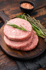 Uncooked beef and pork meat patty on a wooden board, inviting you to create your favorite gourmet burger recipes. wooden background. top view