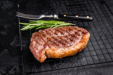 Juicy grilled striploin New York steak with perfect grill marks, ideal for a hearty meal or summer barbecue. black background. top view