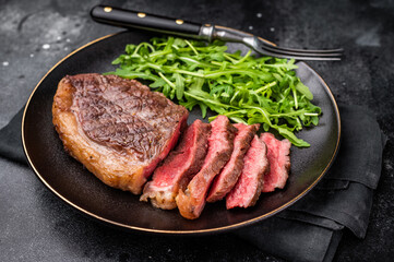 Appetizing grilled striploin steak with salad, inviting you to indulge in a mouthwatering culinary experience. black background. top view