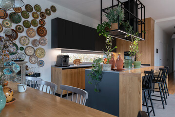 Kitchen and dining room in luxurious style, modern furniture, wooden counter with chair. Indoors architecture with stylish design and decoration on the wall. Smart home with contemporary decor.