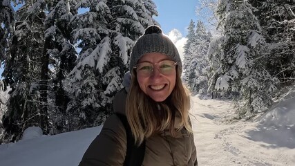 Happy woman vlogging and walking in a snowy winter forest