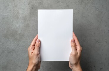 Person holds blank white A5 paper. Clean sheet for notes or design against textured gray background. Useful for mockups, invites, or flyers.
