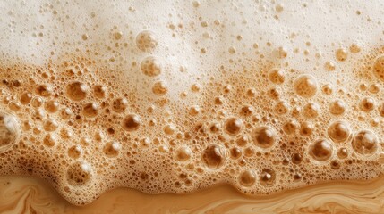 A close-up view captures the creamy foam and bubbles of freshly brewed coffee, highlighting the warm brown hues and rich textures. The frothy surface appears inviting, perfect for coffee lovers.