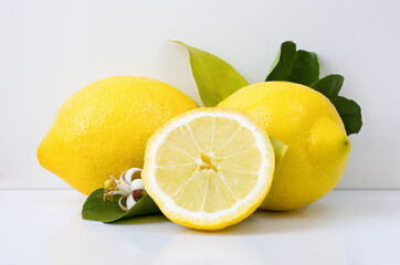 A lemon slice and a couple of lemons on a light background