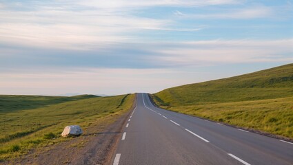 Fototapeta premium Scenic winding road through hills under a clear sky during sunset