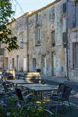 A street with a row of tables and chairs outside a building in City Saintes in France. The tables are empty and the chairs are black