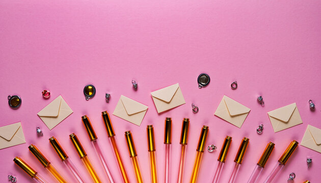 Stylish stationery flatlay with gold pens and envelopes on a pink surface, perfect for invitations, creative projects, or personalized notes