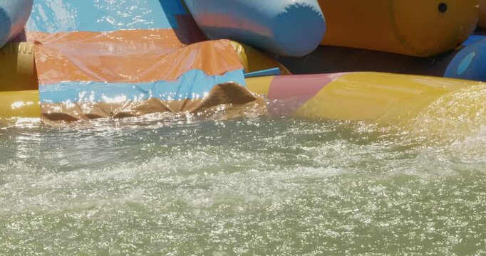 A child rides a water slide. A little girl wearing glasses is having a great time sliding down an inflatable water slide and splashing in the pool on a beautiful sunny day during summer vacation.