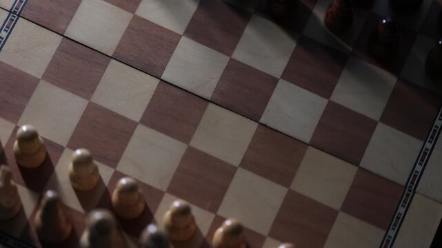 Dynamic video sequence of chess pieces positioned on a slowly rotating chessboard, symbolizing the intellectual confrontation between black and white opposing forces in strategic gameplay. Top view