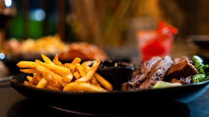 Carne asada servida con papas fritas y salsa en restaurante nocturno