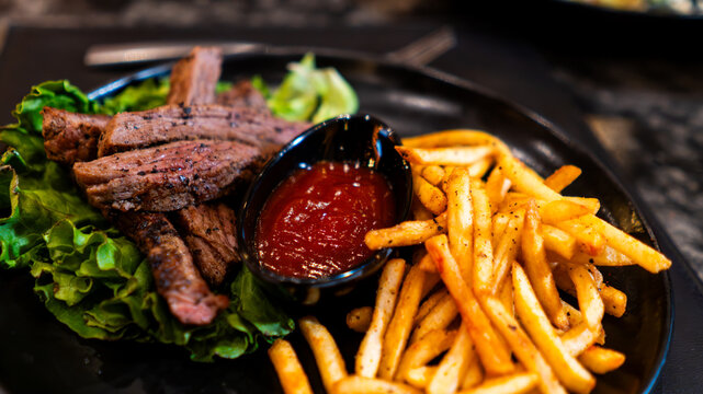 Carne asada servida con papas fritas y salsa en restaurante nocturno