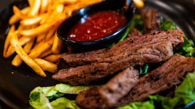 Carne asada servida con papas fritas y salsa en restaurante nocturno