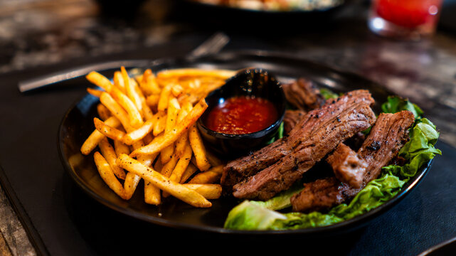 Carne asada servida con papas fritas y salsa en restaurante nocturno