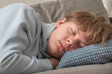 Young caucasian man sleeping peacefully on sofa at home, resting with eyes closed on soft pillow in calm comfortable living room environment. Autumn depression. Leisure Activities At Home