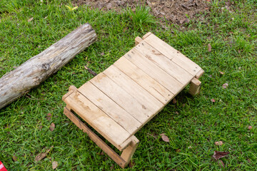 Handmade wooden bench on grassy ground with fallen log in tropical outdoor setting