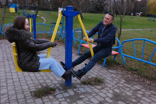Family values father and daughter are walking in nature lake in fall in cold weather, drinking coffee, laughing, playing on playground, reminiscing about childhood, working out on horizontal bars. - Powered by Adobe