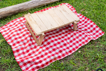 Rustic wooden picnic table on checkered blanket with log and shoe detail in tropical outdoor setting