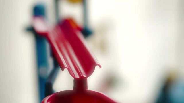 Macro shot of a silver, metallic marble ball rolling down a red plastic slide (board game)