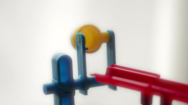 Silver, metallic marble ball launching out of a plastic yellow bucket (board game)