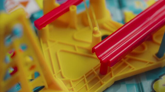Silver marble rolling down a red slide into a plastic bucket (board game)