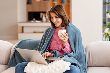 Happy, smiling woman working remotely on laptop at home sofa