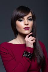 Close-Up Studio Portrait of a Serious Brunette Woman with Smokey Eye Makeup and Dark Lipstick, Posing with Hand