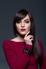 Close-Up Studio Portrait of a Serious Brunette Woman with Smokey Eye Makeup and Dark Lipstick, Posing with Hand
