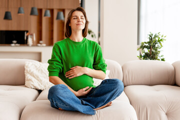 Obraz premium Pregnant woman meditating on sofa enjoying peaceful moment