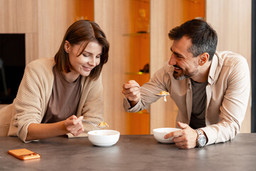 Happy couple enjoying breakfast together eating cereal