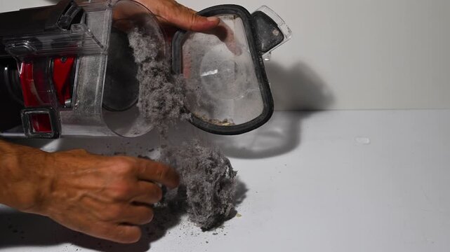 The vacuum cleaner's dustbin spills out the accumulated dust, dirt, and hair. Home cleaning and hygiene.