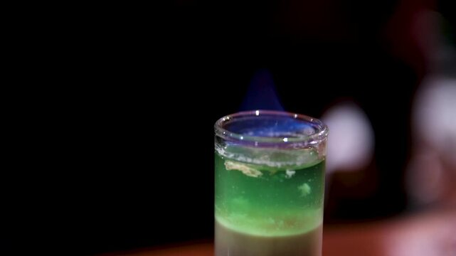 Flaming green cocktail Spectacular footage with the preparation of absinthe: the barman expertly caramelizes the sugar cube on the tea spoon with the alcohol flame. High quality 4k 