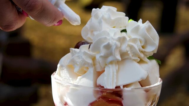 Garnishing no-bake strawberry shortcake trifle in jar with leaf of fresh mint; easy homemade dessert made with fresh strawberries and topped with whipped cream. High quality 4k footage