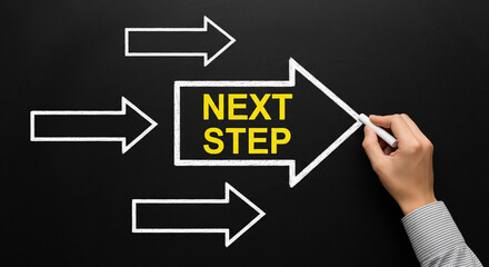Hand drawing a next step arrow on a chalkboard, business concept