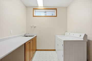 Small, white laundry room with a sink and a washer and dryer