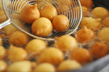 Fritule - Croatian mini doughnuts. Oil frying process. Selective focus