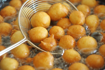 Fritule - Croatian mini doughnuts. Oil frying process. Selective focus