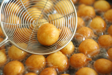 Fritule - Croatian mini doughnuts. Oil frying process. Selective focus
