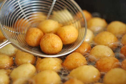Fritule - Croatian mini doughnuts. Oil frying process. Selective focus