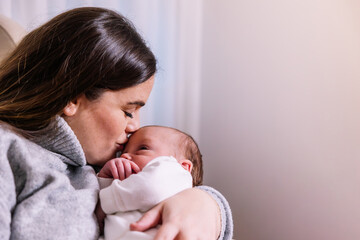 Mother kissing newborn baby showing love and tenderness