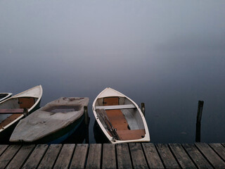 empty wooden rowing boats fixed to the coast in a misty winter weather with dense fog