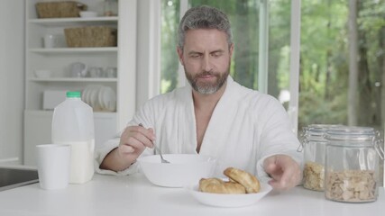 Morning breakfast in modern kitchen. Man eating healthy breakfast at home kitchen. Man eat breakfast in the kitchen. Man eating cereal with milk. Hispanic man enjoy healthy meal at kitchen table - Powered by Adobe