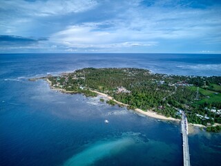 Island coastline with bridge, palm trees and turquoise shallows