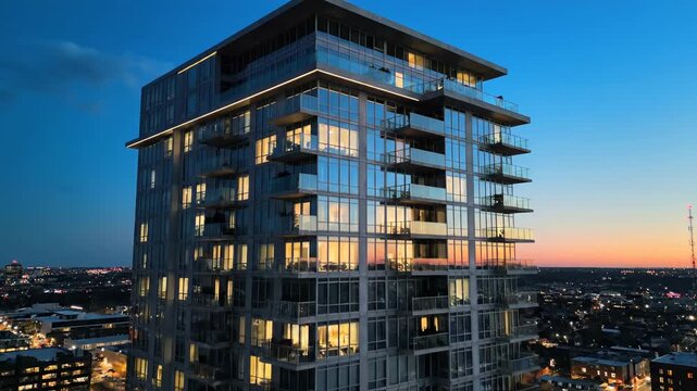 Modern highrise building exterior with glass facade and balconies at dusk