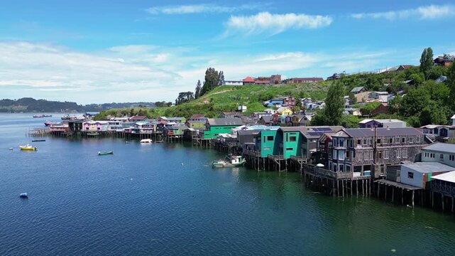 Castro, Chile: Forward aerial drone footage above colorful waterfront stilt houses in Castro, Chiloe island, Lake District of Chile.