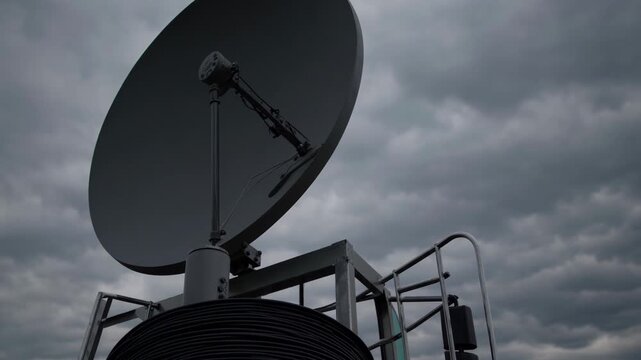 Large parabolic satellite dish against stormy, overcast sky capturing and transmitting signals, symbolizing global communication, connectivity and resilient telecom infrastructure