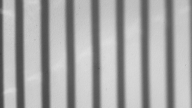 Abstract vertical window blind shadow lines moving on white concrete wall texture